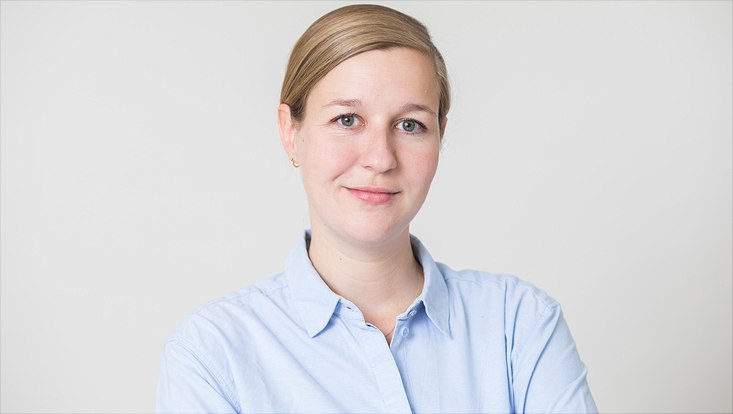 Frau im blauen Hemd vor weißer Wand