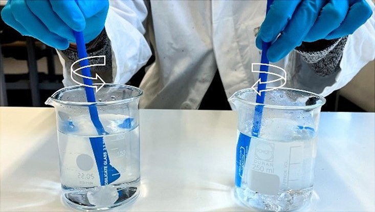 Hände rühren mit Strohhalmen Eiswürfel im Glas